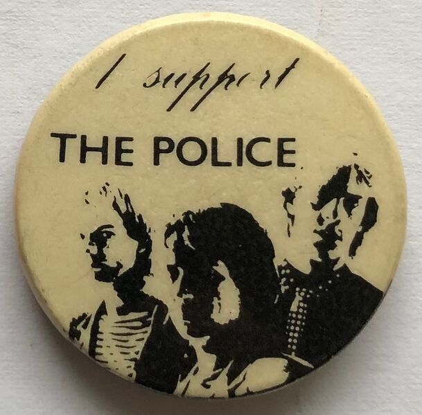 File:1979 09 Police fin costello beige background round button.jpg